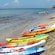 A row of kayaks sporting different designs lines the beach
